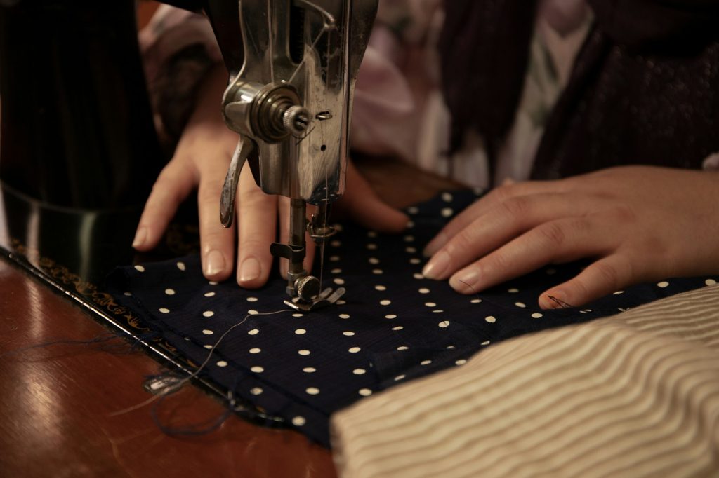 A woman's hands sew a piece of fabric with a sewing machine.