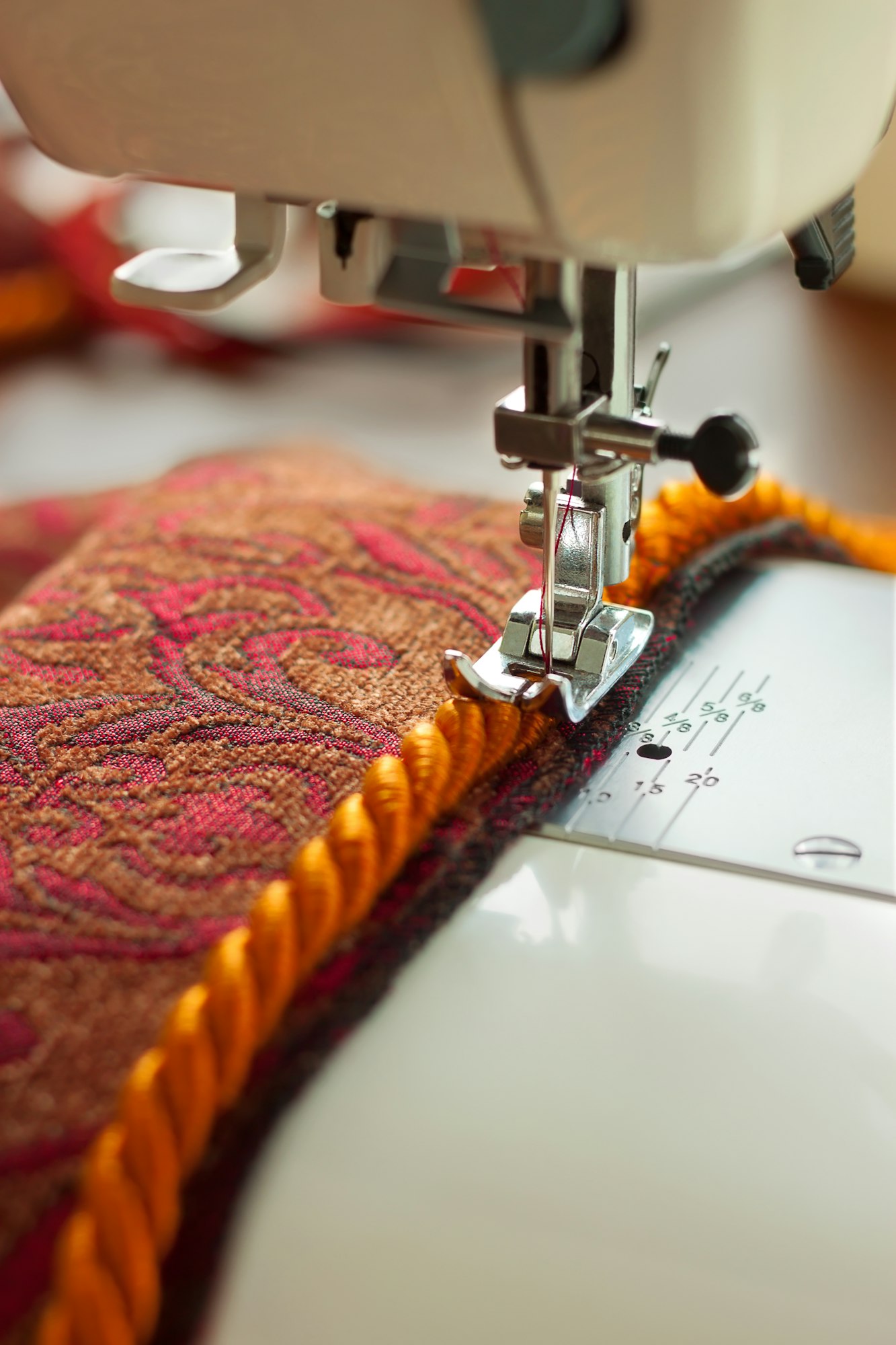 sewing machine. the process of sewing a decorative cord of red fabric.