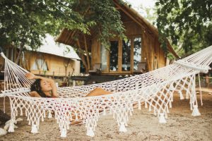 Woman relaxing in the white handmade macrame hammock on tropical beach