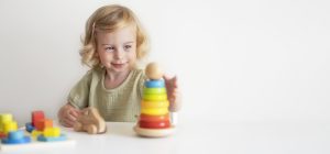 Cute happy blonde caucasian toddler,baby girl playing with colourful wooden eco-friendly toys
