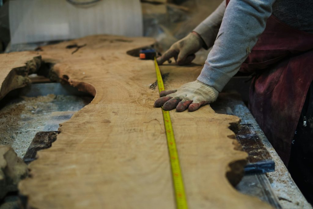 Marking out cuts on a wood slab, accuracy focused. Demonstrates the skill behind custom woodworking