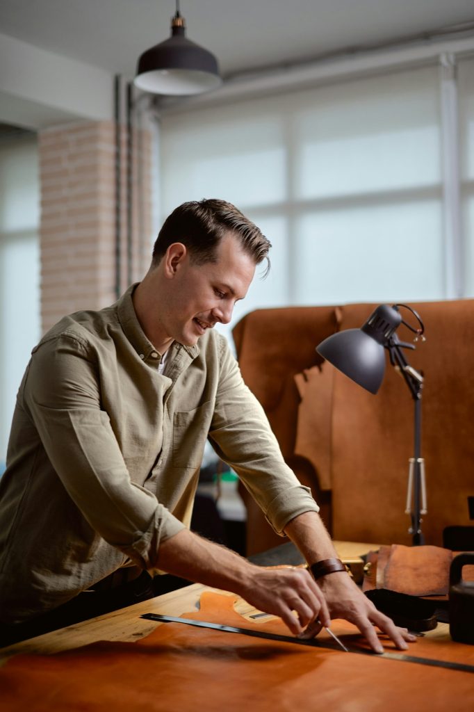 smiling tailor enjoys working with leather